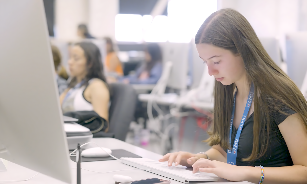 A high school student types on a computer during a graphic design course